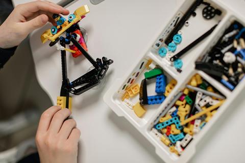 hands building with lego-style bricks