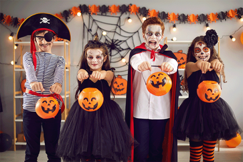 children in Halloween costumes holding trick-or-treat pumpkins